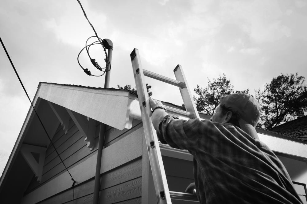 Image of man climbing ladder to roof where power lines attach to home