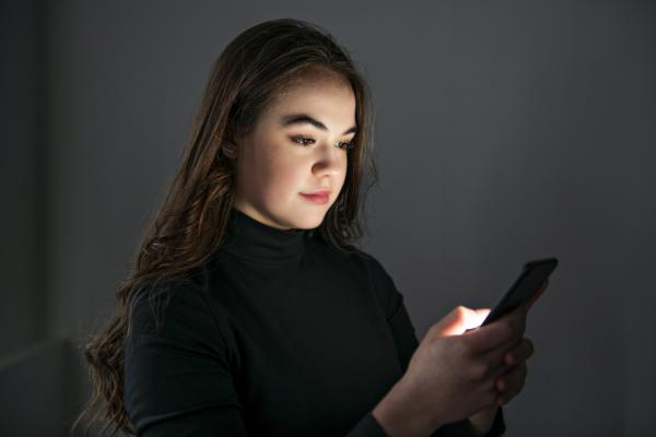 Girl holding cell phone in the dark
