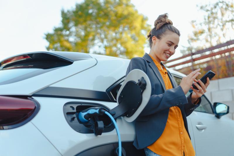 Woman leaning against EV while charging