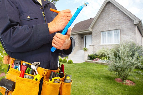 Electrical inspector with clipboard in front of residence