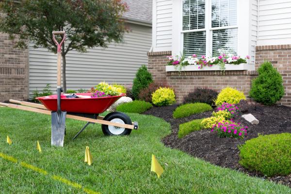 Red wheelbarrow in yard with yellow flags marking underground faciliites