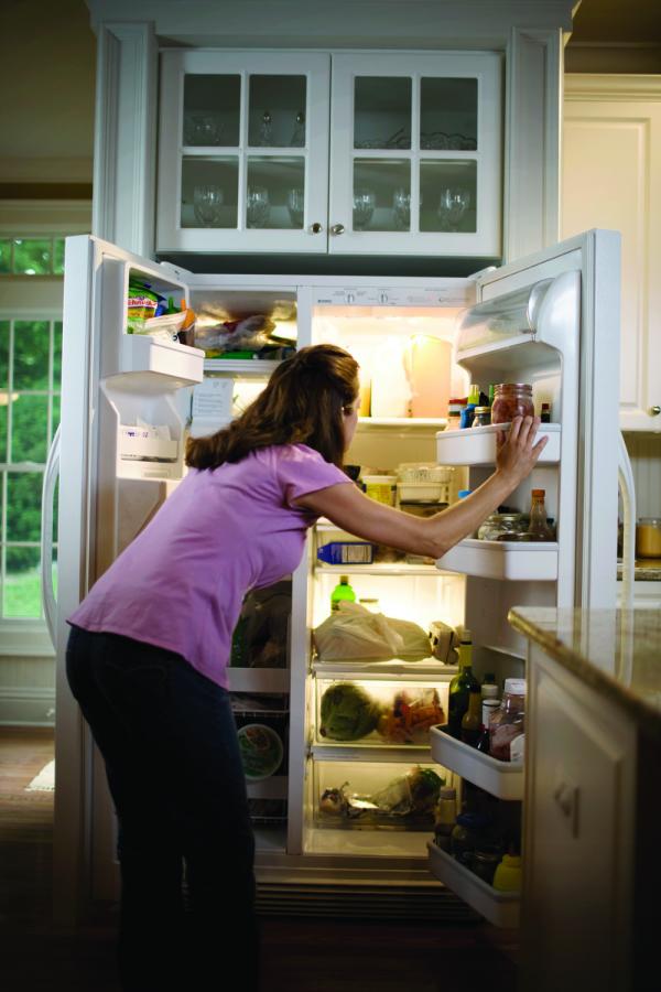 Woman looking inside side by side refrigerator