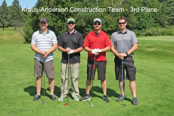 3rd place team, Kraus Anderson, on golf course holding golf clubs