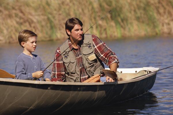 Man and young boy is boat fishing on lake