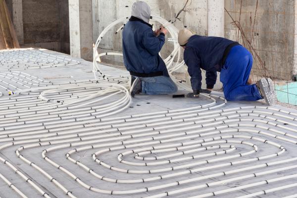 Two men working to install tubing for underfloor heat