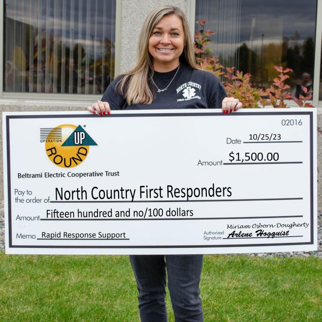 Tara Hokuf holds check from Operation Round Up grant